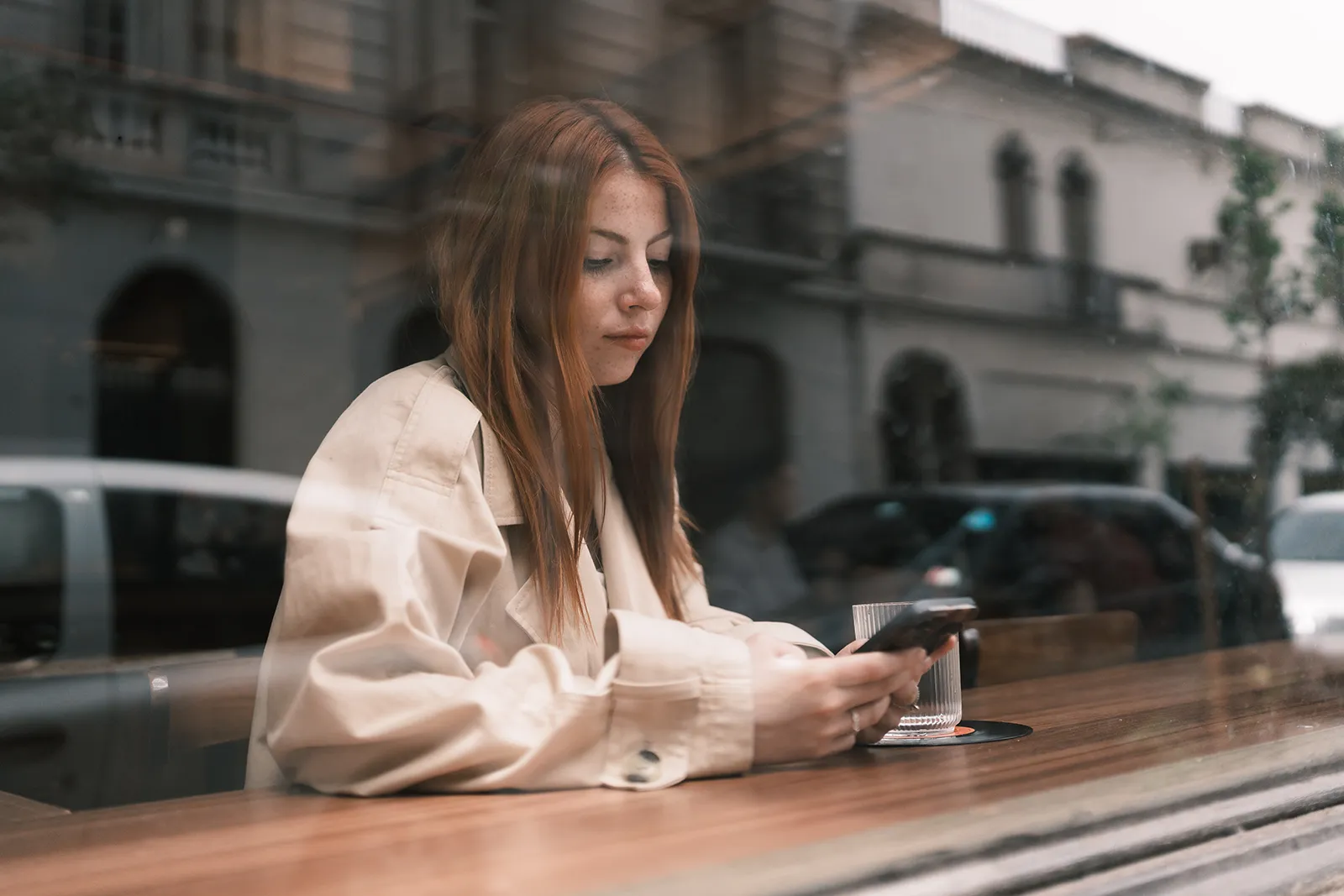 Mujer sentada en mesa de café al aire libre usando una laptop