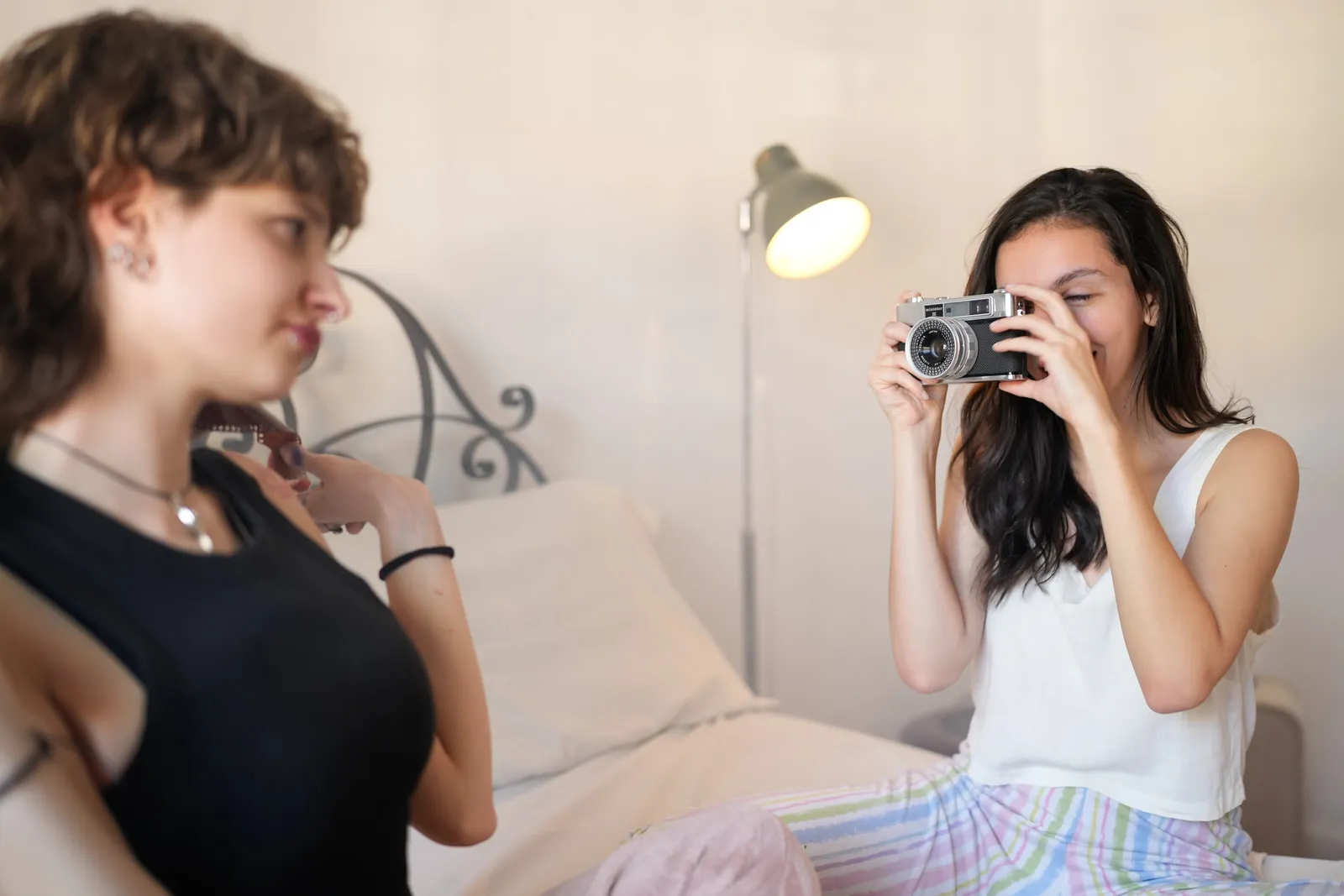 Dos chicas jóvenes sacándose fotos con una cámara en la habitación