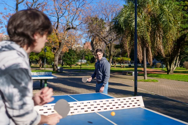 Pareja jugando al ping pong en un parque urbano