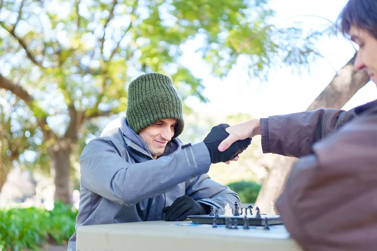 Dos personas jugando al ajedrez en una mesa de plaza