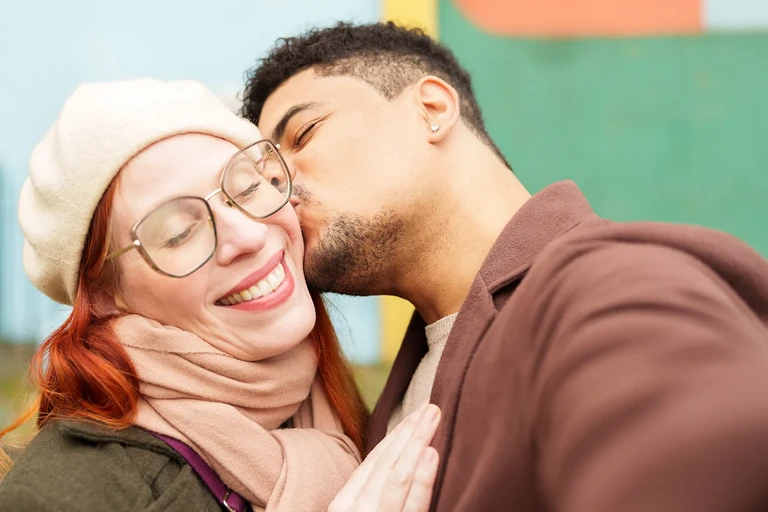 Pareja abrazada y dándose un beso en un parque