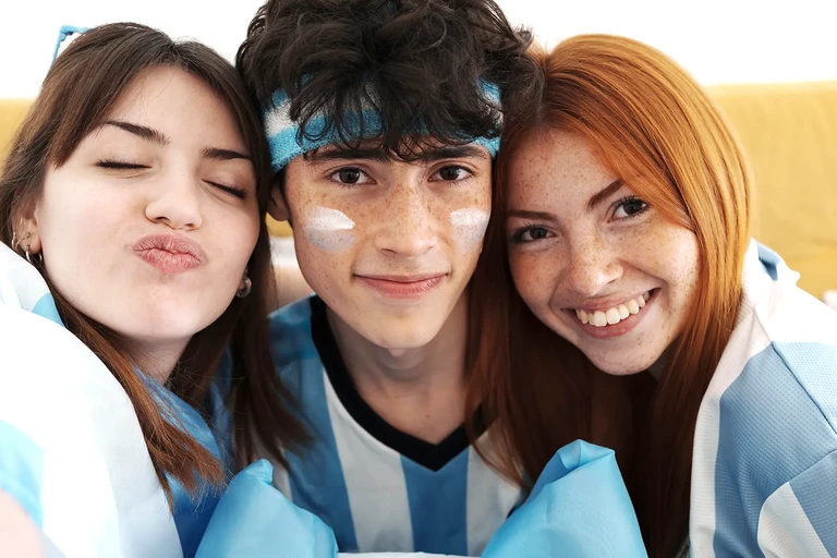 Tres jóvenes hinchas sonriendo y posando juntos para una foto