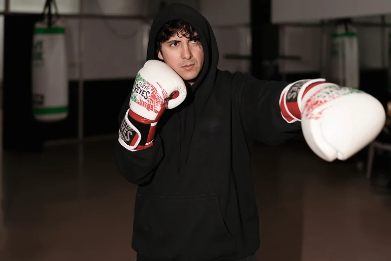Retrato de joven con guantes de boxeo blancos sobre fondo oscuro
