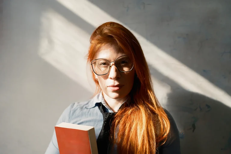 Retrato de mujer joven leyendo un libro con luz natural de ventana