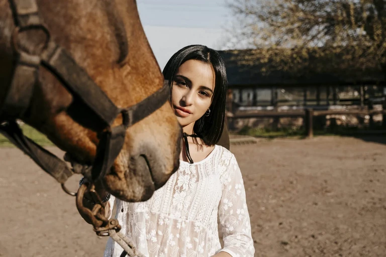 Mujer posando junto a un caballo en un entorno rural